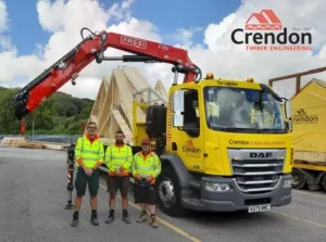 Three men stood in front of lorry with roof trusses on back